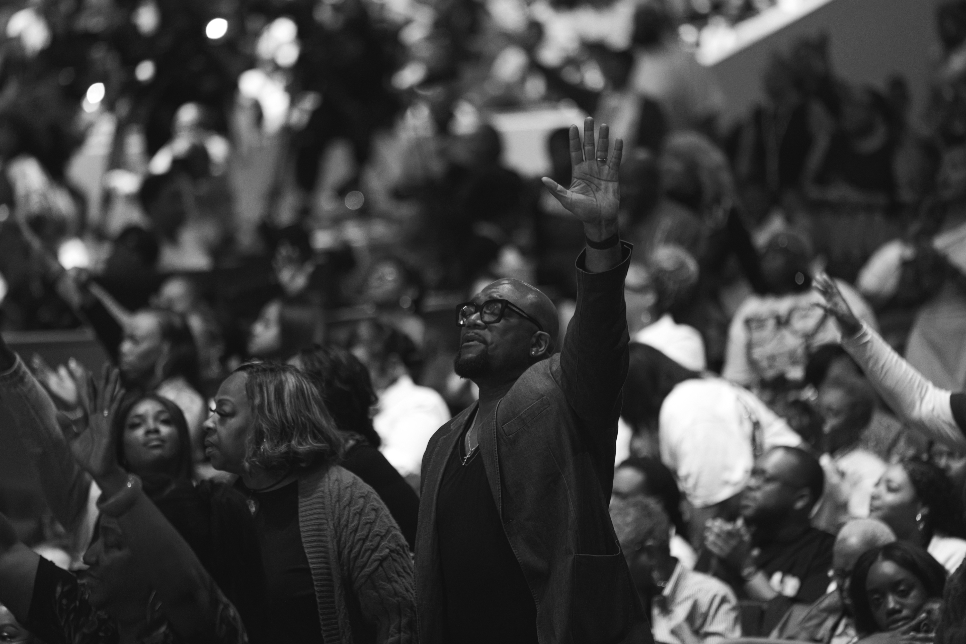 Congregation worshipping with raised hand in monochrome